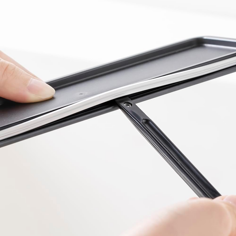 A person using the scraper end of the &NE Nikii cleaning brush to remove residue from a narrow groove in a container lid.