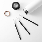 A flat lay showing a set of three &NE Nikii mini cleaning brushes next to a disassembled white water bottle.