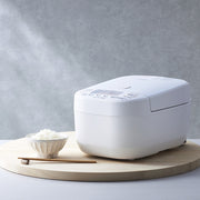Zojirushi NW-YAQ10 Pressure IH Rice Cooker 5.5 Cups in white with a bowl of cooked rice