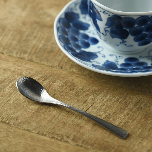 Nagomi hammered stainless steel coffee spoon (12cm) beside a blue and white coffee cup