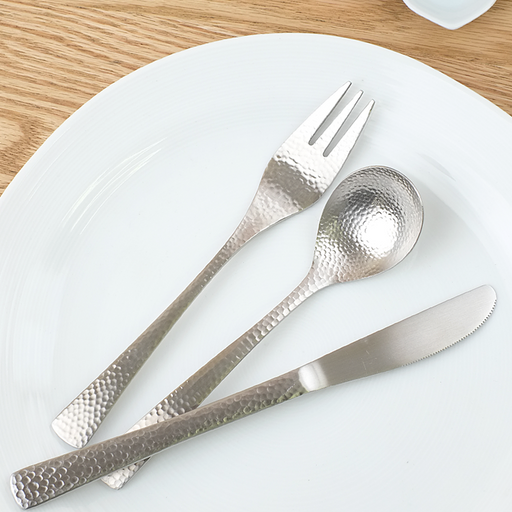Nagomi Hammered Style stainless steel cutlery set showing spoon, fork, and knife with tsuchime hammered texture, arranged on a rustic wooden table