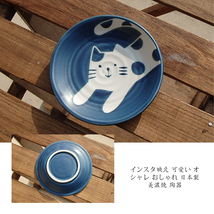 Top view of a blue ceramic side plate with a cat design on a wooden table surface, alongside a bottom view showing the plate's base.