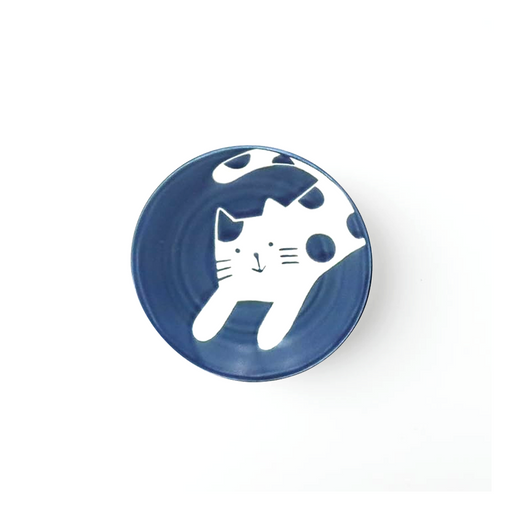 Blue ceramic side plate with a white cat design in a playful pose, set against a solid blue background.