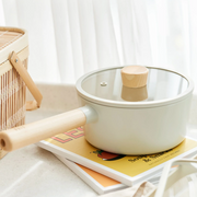 Neoflam Fika 18cm ceramic nonstick saucepan with a matching glass lid, wooden handle, and knob, shown on a clean white background.