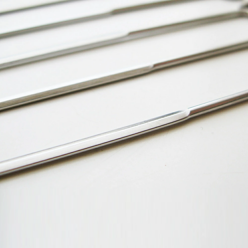 A close-up view of the flat profile of the Nippan barbecue skewers, showing the sturdy steel design that prevents food from spinning during grilling.