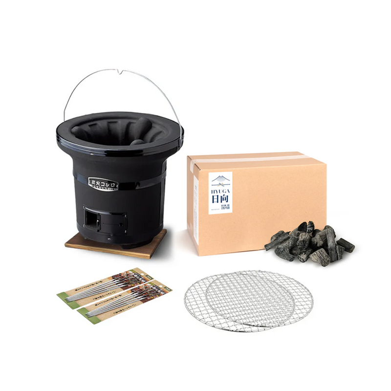 The Mikawa Portable Konro Grill starter set, showing the round black grill on a wooden base, a box of Hyuga binchotan charcoal, two grill meshes, and packs of skewers.