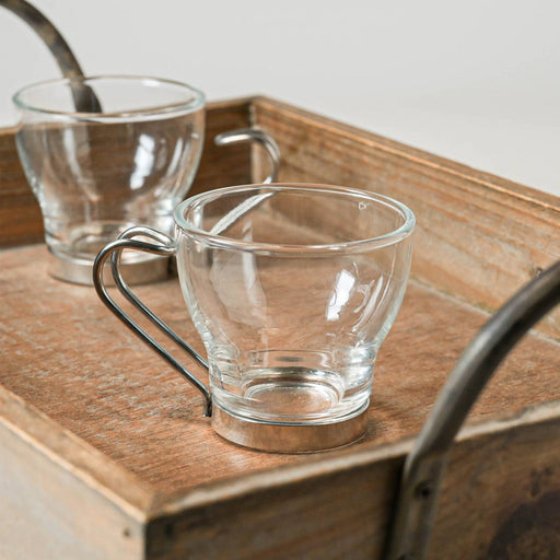 Two Oslo 110ml glass espresso cups with stainless steel handles on a wooden tray