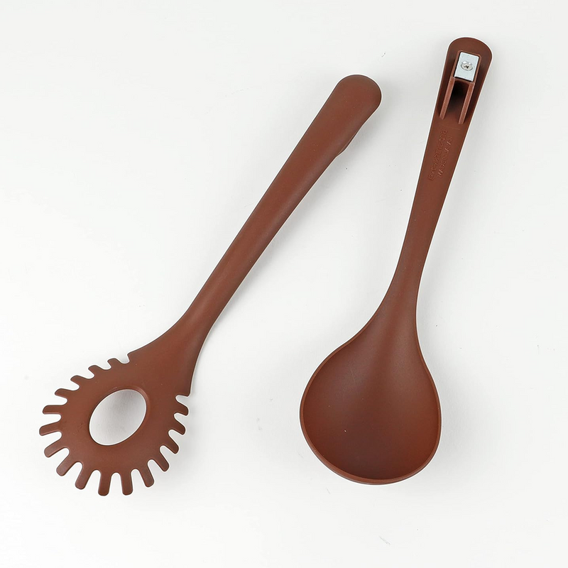 The brown Pearl Life tongs separated into two individual utensils, a pasta fork and a serving ladle, lying side-by-side on a white surface.
