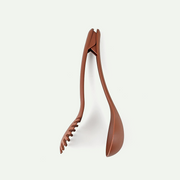 The Pearl Life utensil assembled as a pair of brown cooking tongs, standing on a white background.
