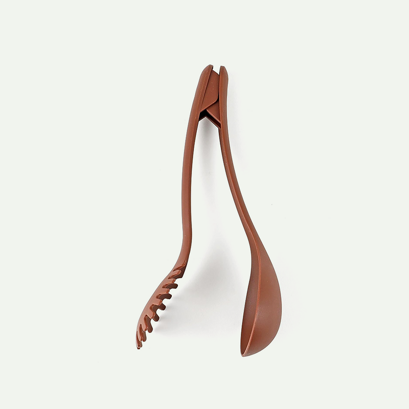 The Pearl Life utensil assembled as a pair of brown cooking tongs, standing on a white background.
