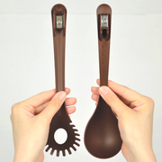 A person holds the two separated brown utensils, showing the powerful magnetic connectors at the top of each handle.
