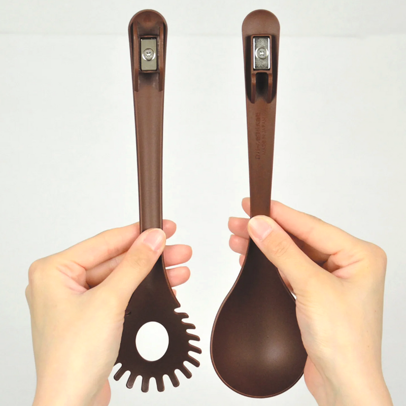A person holds the two separated brown utensils, showing the powerful magnetic connectors at the top of each handle.
