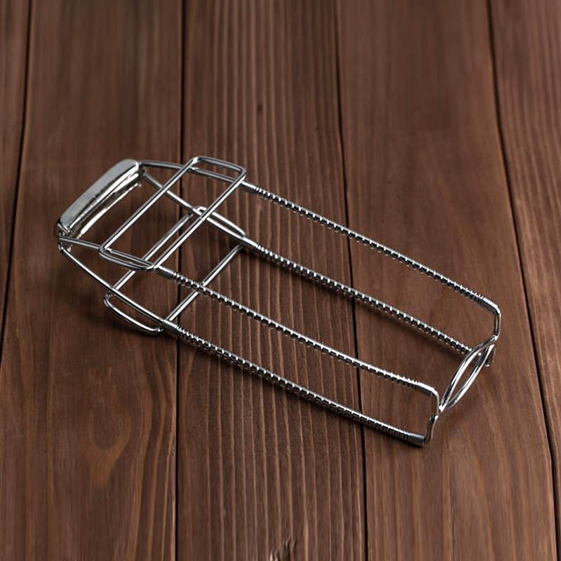 The Pearl Life stainless steel dish gripper resting on a dark wooden surface.