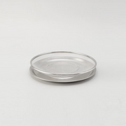 The two-piece Ryoumiya stainless steel set, featuring a round fine-mesh strainer resting neatly on top of its matching solid serving tray.