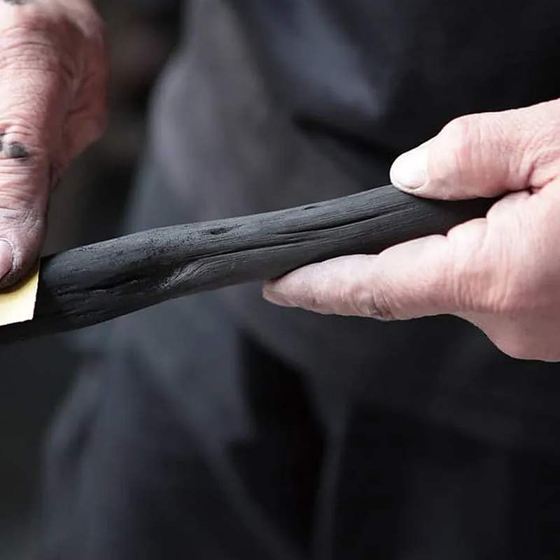 Artisan polishing a piece of Kishu binchotan charcoal by hand using sandpaper.