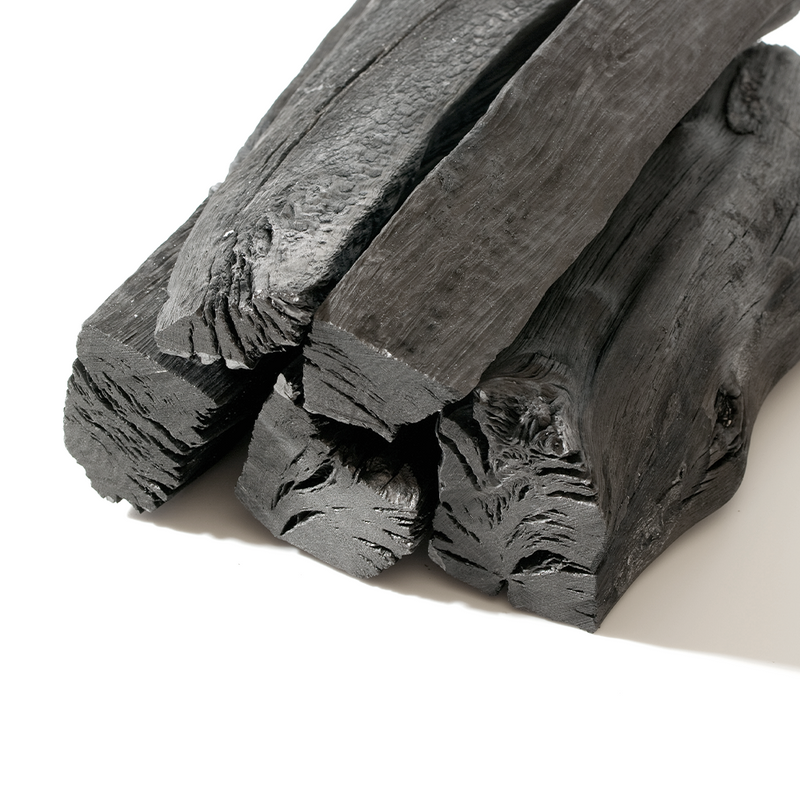 Close-up view of stacked Tosa binchotan Japanese white charcoal logs with distinctive wood grain patterns.