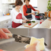 A family cooking scene using a Remy Kuro Japanese Santoku knife, where a mother and her child are slicing vegetables on a kitchen counter, showcasing the knife's utility in a home setting.