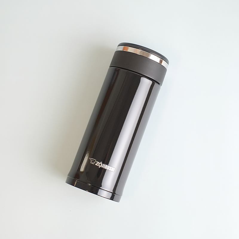 A glossy black Zojirushi SM-JD36 vacuum insulated flask with a screw-top lid lying diagonally on a white background.