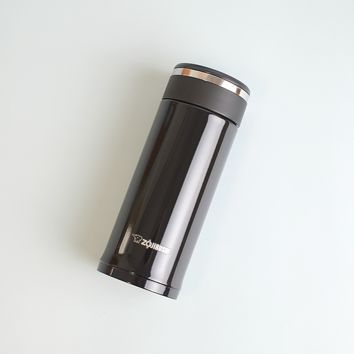 A glossy black Zojirushi SM-JD36 vacuum insulated flask with a screw-top lid lying diagonally on a white background.