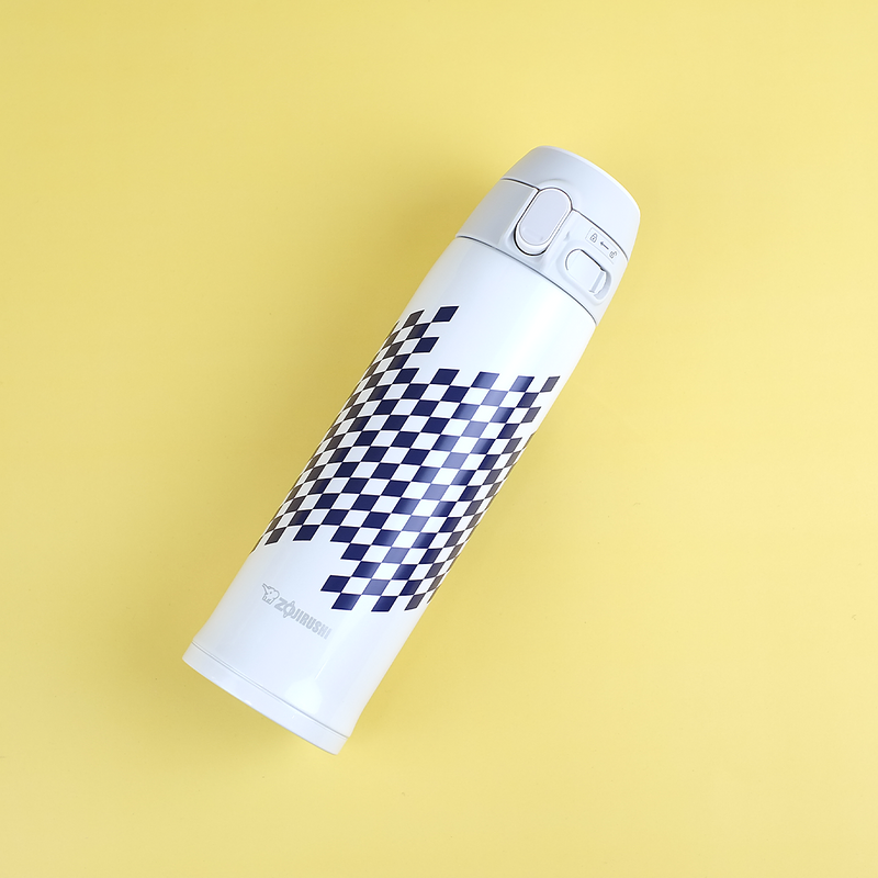 A white Zojirushi SM-TAE48SA vacuum flask featuring a blue checkered "Ichimatsu" pattern and a rabbit silhouette, lying diagonally on a yellow background.