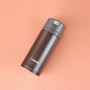 A sleek black Zojirushi SM-XB36 vacuum insulated flask positioned diagonally on a soft peach background.