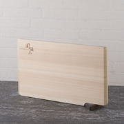 The Seki Magoroku self-standing cutting board, made from natural Hinoki cypress wood, shown standing upright on its integrated walnut wood lever.
