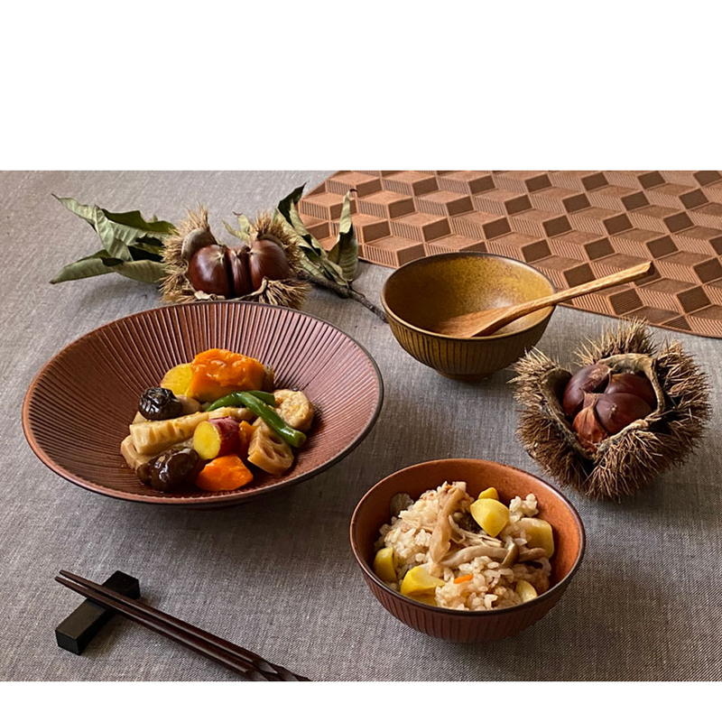 Autumn-themed table setting featuring Japanese ceramic bowls filled with vibrant vegetables and rice, complemented by chestnut husks and natural textures.
