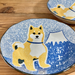 Close-up of a ceramic bowl showcasing a painted Shiba Inu and stylized Mount Fuji, highlighting the intricate blue and white pattern and textured surface.