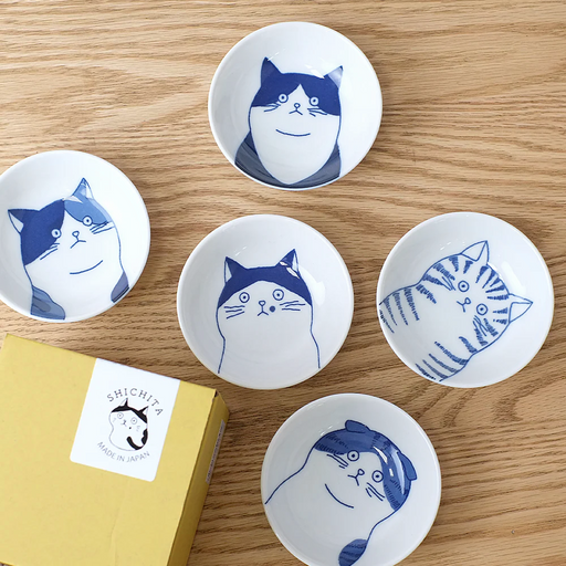 The Shichita Mino Yaki Cat 5-piece side bowl set, showing five bowls with different cat illustrations displayed next to their yellow gift box.