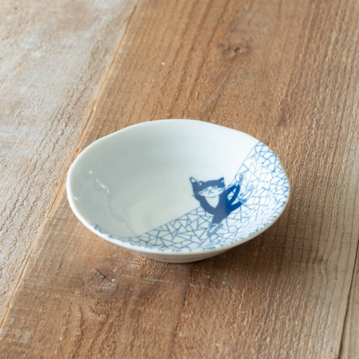 A small Shichita Mino Yaki cat bowl with a blue Hyouretsumon pattern resting on a wooden table.