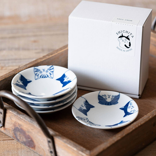 Takamizu Kiln SHICHITA cat mini plate set of five 10cm Japanese porcelain plates with blue cat illustrations, stacked on a wooden tray beside the Mino ware gift box.

