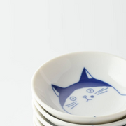 A close-up view of a stack of Shichita Mino Yaki cat-themed side plates, showcasing the adorable hand-painted cat design on the top plate.