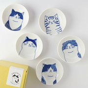 The Shichita Mino Yaki Cat 5-piece side bowl set, showing five bowls with different cat illustrations displayed next to their yellow gift box.