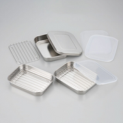 Various components of the Shimomura food prep set, including stainless steel trays, a wire rack, and lids, displayed on a grey surface.

