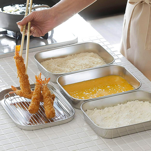 The Shimomura stainless steel food prep set being used to bread and drain fried tempura shrimp on a kitchen counter.

