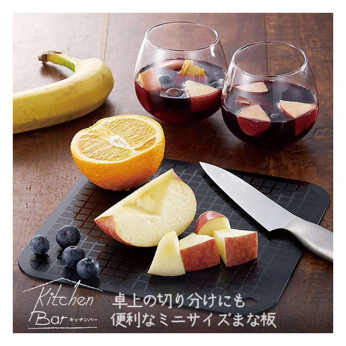 Close-up of black mini cutting mat with knife, sliced apple, orange, blueberries, and drinks, highlighting its textured surface and functionality for small servings.






