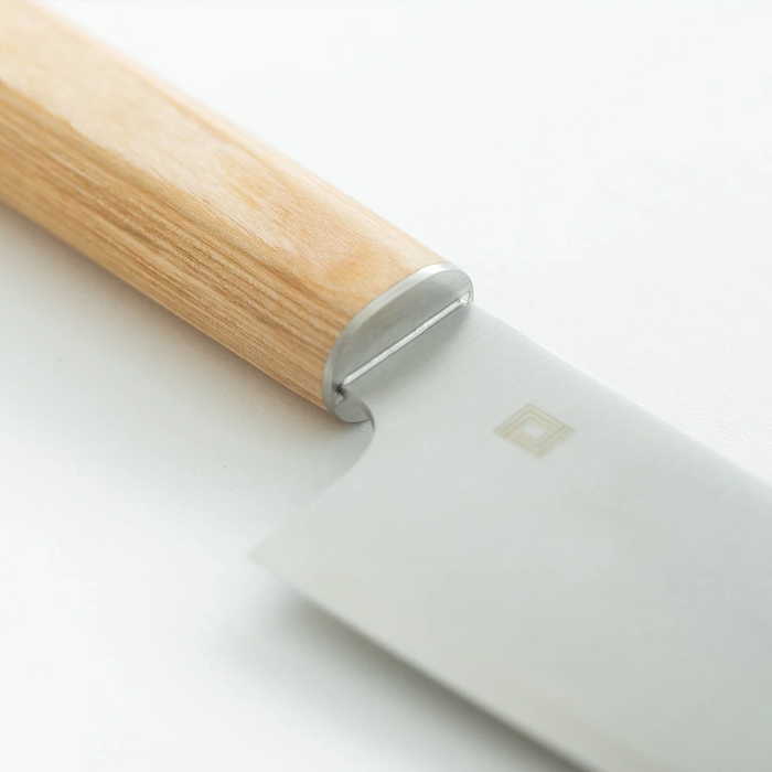 Close-up of the bolster and wooden handle of the Shizu Takumi Yuri Nakiri Knife, highlighting its seamless construction.