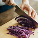 Shizu Takumi Yuri Nakiri Knife in use, slicing a head of red cabbage with precision.