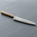 The Shizu Takumi Yuri Japanese Santoku Knife displayed against a dark grey background, highlighting its sleek and minimalist design, with the natural wooden handle contrasting beautifully with the polished blade.