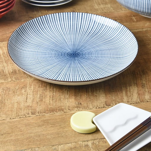 A Showa Seito Sendan Tokusa plate with its blue and white radial pattern, shown on a wooden table alongside chopsticks and chopstick rests.