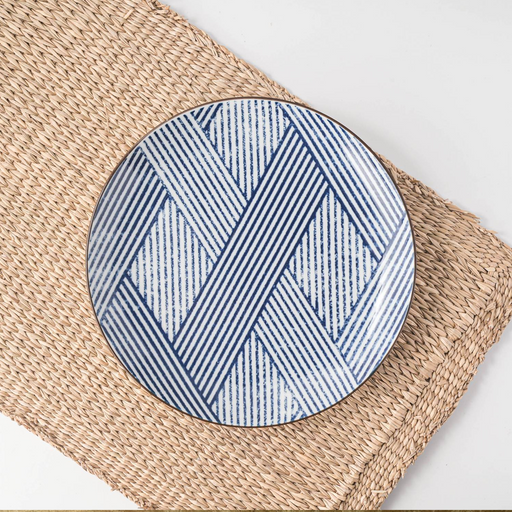 A Showa Seito Shimakoushi side plate with its classic blue and white lattice pattern, displayed on a natural woven placemat.