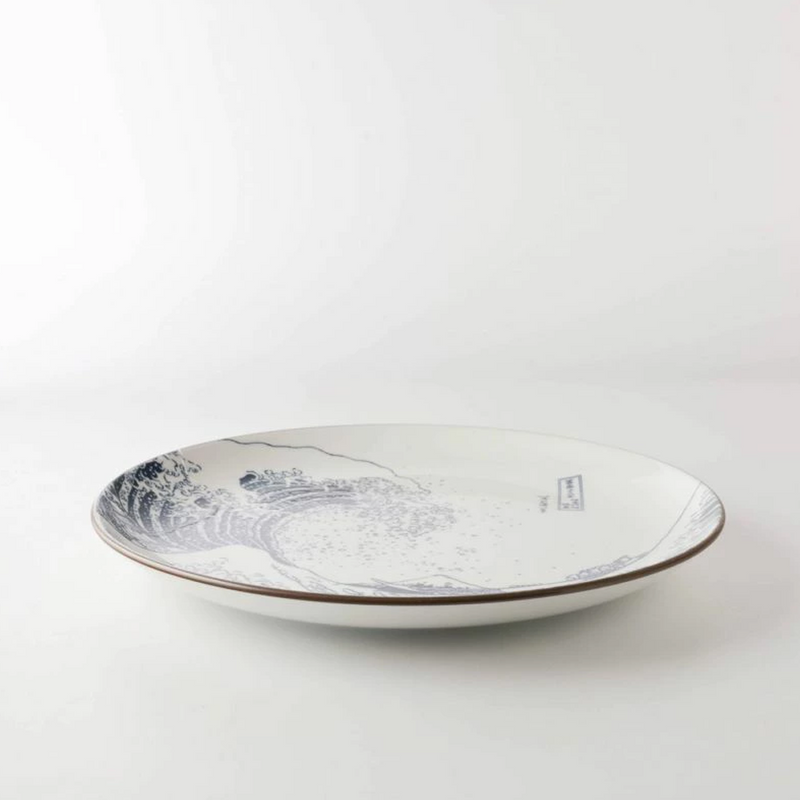 A low-angle side view of 'The Great Wave' 25cm dinner plate, highlighting its gentle curve and dark brown rim against a white background.

