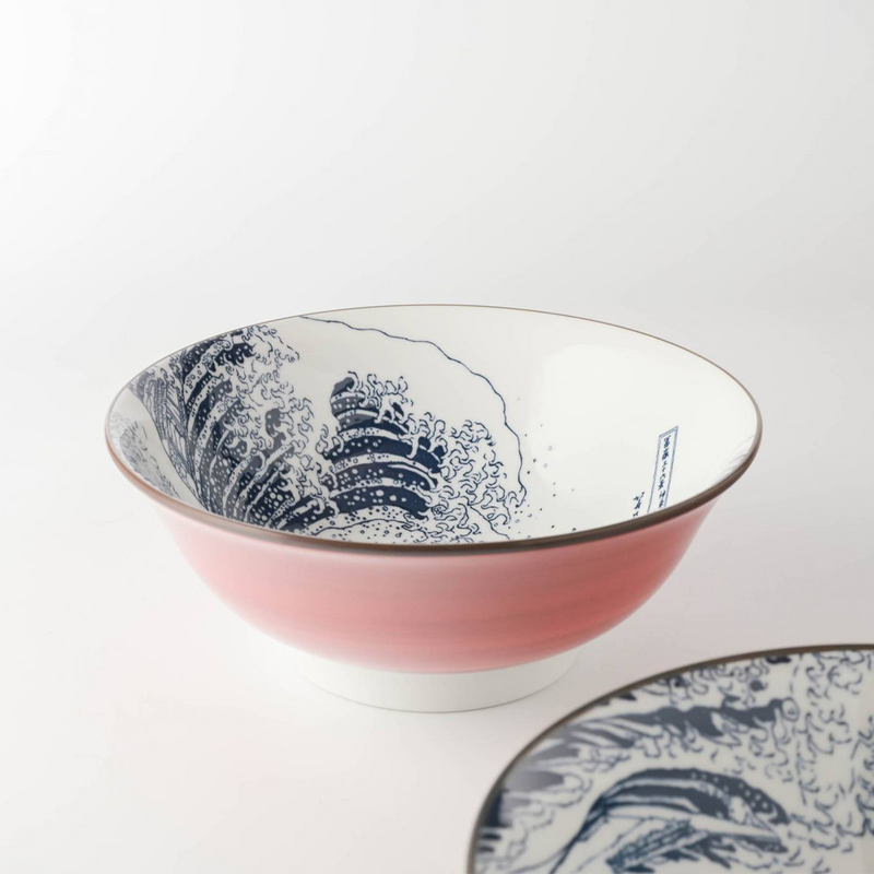 A close-up of a pink ceramic bowl with a dark blue wave pattern inspired by The Great Wave off Kanagawa.