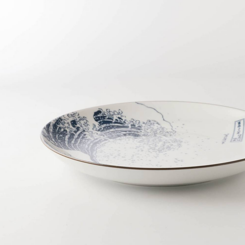 A low-angle side view of 'The Great Wave' dinner plate, highlighting its gentle curve and dark brown rim against a white background.

