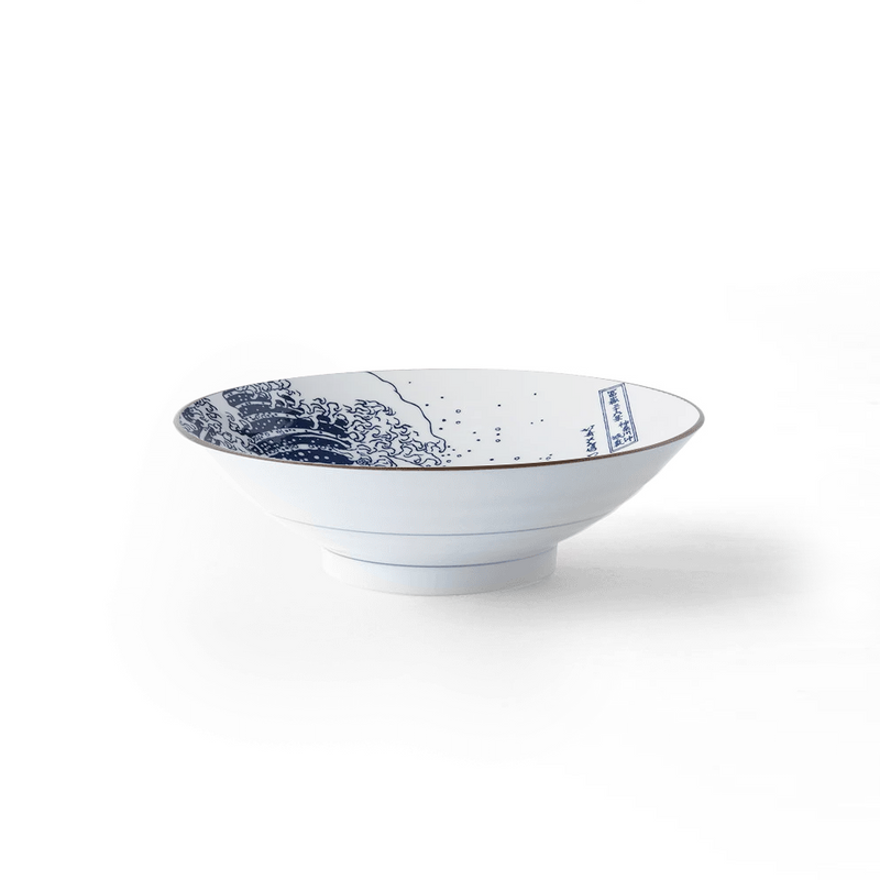 A side-profile studio shot of the Showa Seito 'The Great Wave' Japanese ramen bowl on a white background, showcasing its classic shape and the iconic blue Hokusai artwork within.