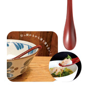 Sunlife red soup spoon with its hooked handle resting on a bowl rim