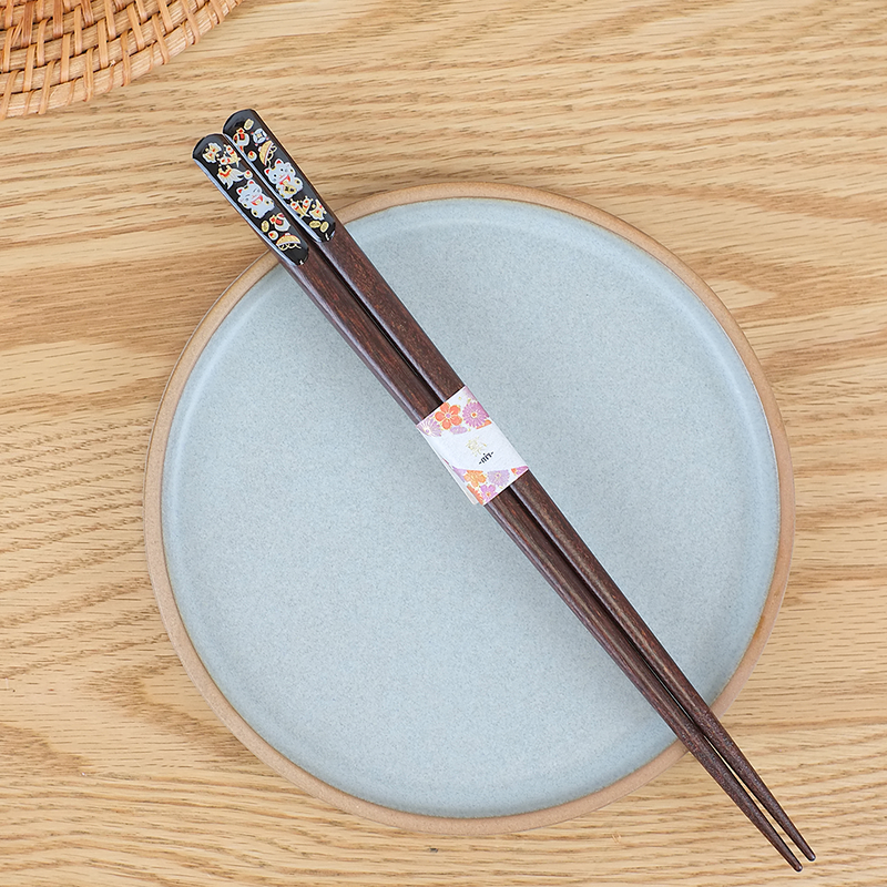 Pair of wooden chopsticks with floral design on the ends, placed on a light blue plate with a wooden rim.