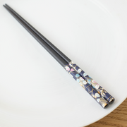 A pair of black Japanese chopsticks featuring a 'Washi Moon Autumn Flowers' design with delicate pink and blue floral patterns on the handle.