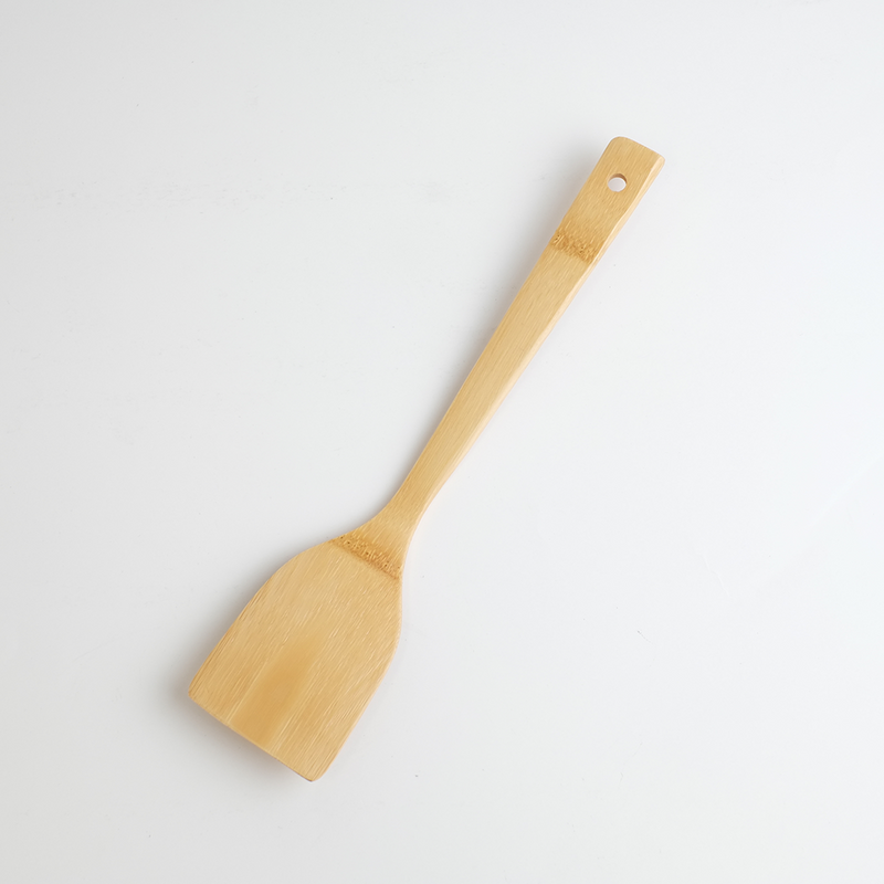Take Kitchen carbonised bamboo turner with a wide angled head and long slim handle with hanging hole, in natural pale bamboo tones against a white background
