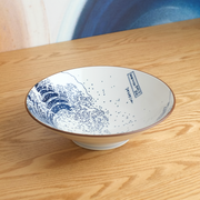 A lifestyle photo of 'The Great Wave' Japanese ramen bowl sitting on a wooden table, showcasing the iconic Hokusai artwork on its interior.
